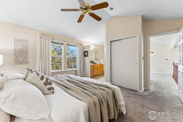 carpeted bedroom with ensuite bath, ceiling fan, a closet, and vaulted ceiling