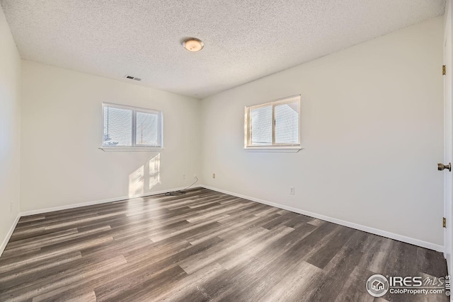 empty room featuring dark hardwood / wood-style floors, plenty of natural light, and a textured ceiling