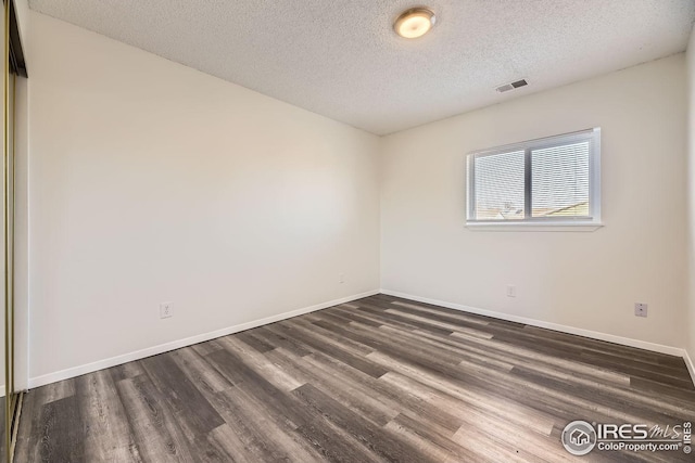 spare room with dark hardwood / wood-style floors and a textured ceiling