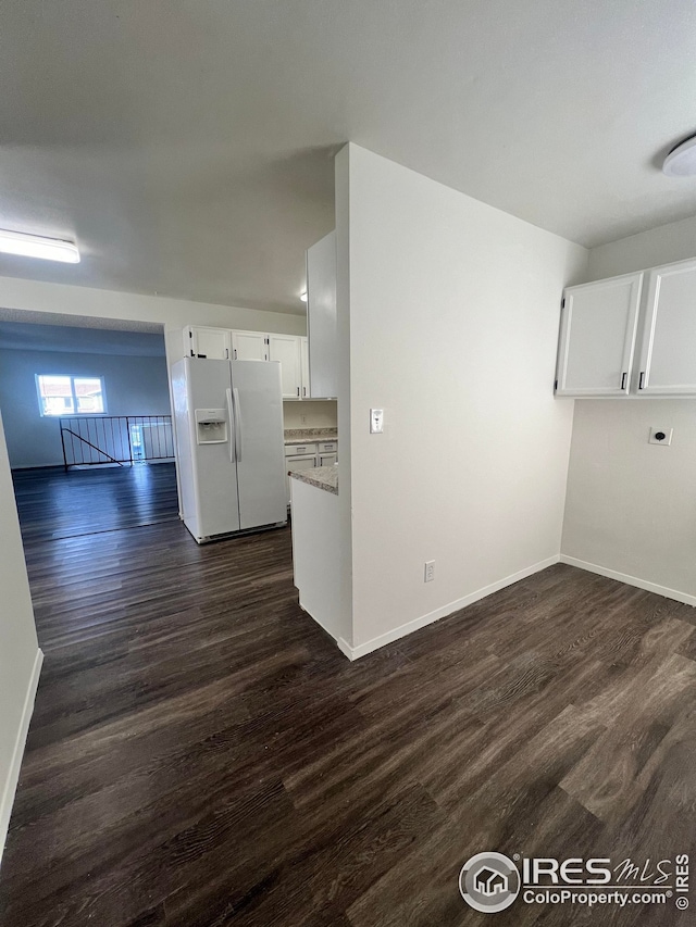 interior space with white refrigerator with ice dispenser, dark hardwood / wood-style flooring, and white cabinetry