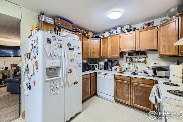 kitchen with a textured ceiling, white appliances, and sink