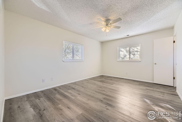 unfurnished room featuring hardwood / wood-style flooring, a textured ceiling, and a wealth of natural light