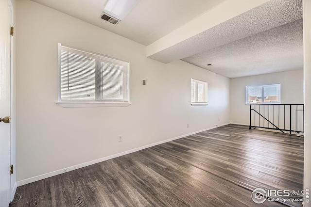 empty room featuring dark hardwood / wood-style flooring and a textured ceiling