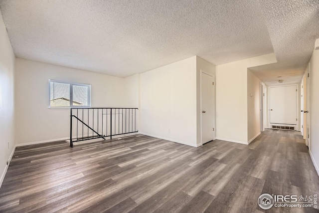 empty room featuring a textured ceiling and dark wood-type flooring