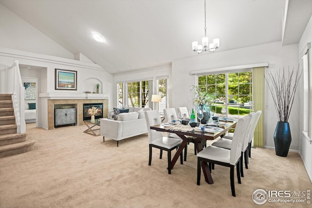 carpeted dining area with high vaulted ceiling, plenty of natural light, and a notable chandelier