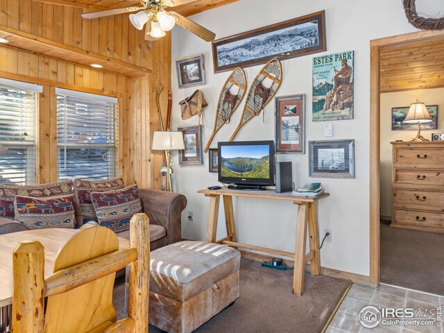 interior space with ceiling fan, wooden walls, light tile patterned flooring, and wood ceiling