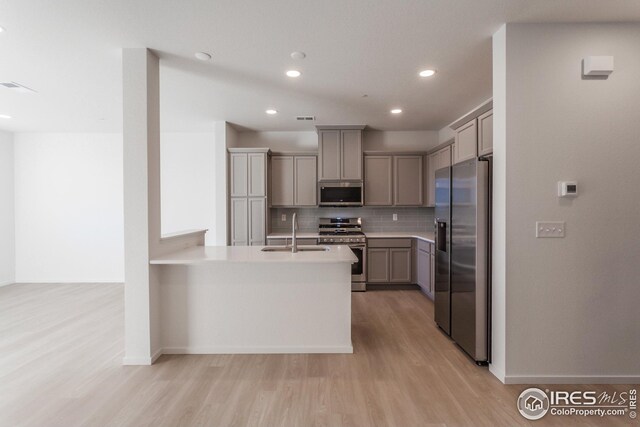 kitchen featuring gray cabinets, appliances with stainless steel finishes, sink, light hardwood / wood-style floors, and kitchen peninsula