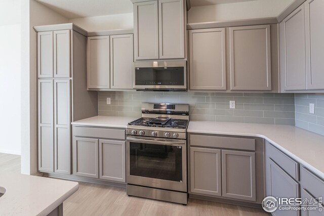 kitchen with appliances with stainless steel finishes, gray cabinetry, and backsplash