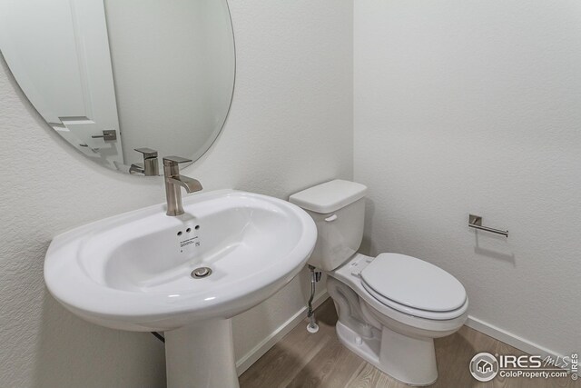 bathroom with hardwood / wood-style floors, sink, and toilet