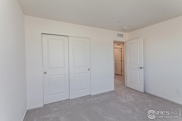 unfurnished bedroom featuring light carpet and a closet