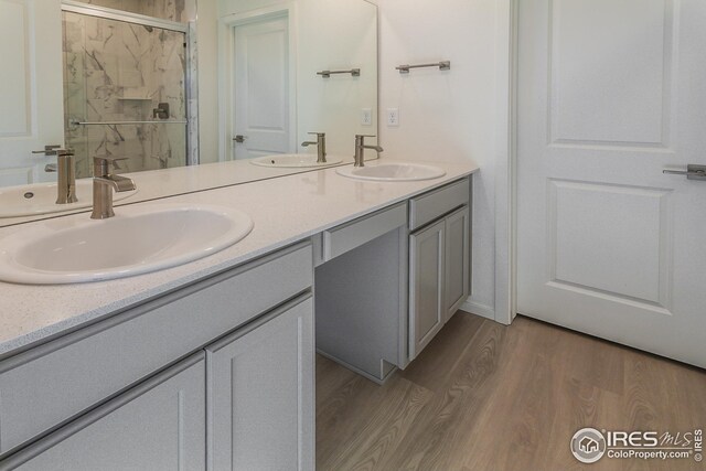 bathroom with wood-type flooring, vanity, and a shower with shower door