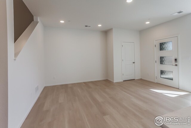 spare room featuring a fireplace and light wood-type flooring