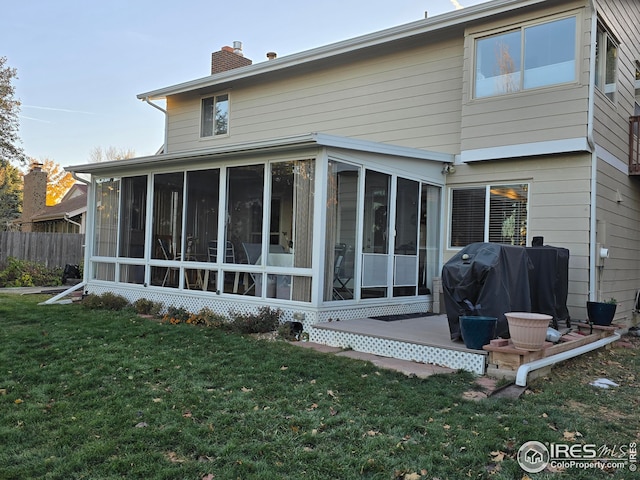 rear view of house featuring a sunroom and a yard