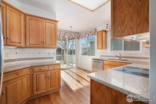 kitchen featuring sink, dishwasher, backsplash, hanging light fixtures, and light stone countertops