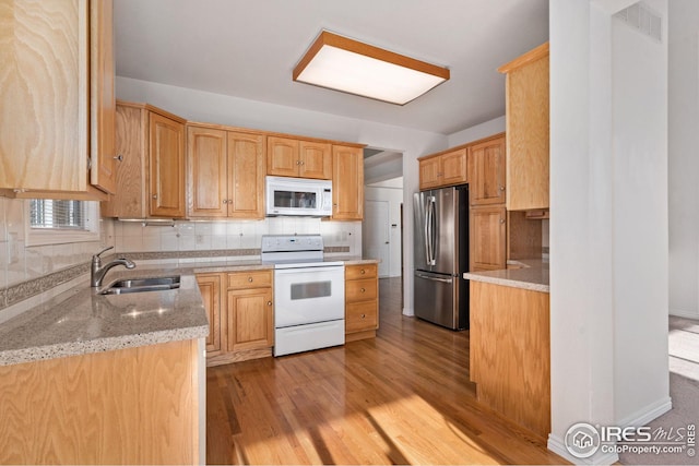 kitchen featuring sink, backsplash, light stone counters, light hardwood / wood-style floors, and white appliances