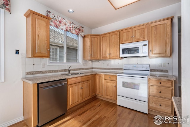 kitchen featuring sink, white appliances, light hardwood / wood-style flooring, tasteful backsplash, and light stone counters