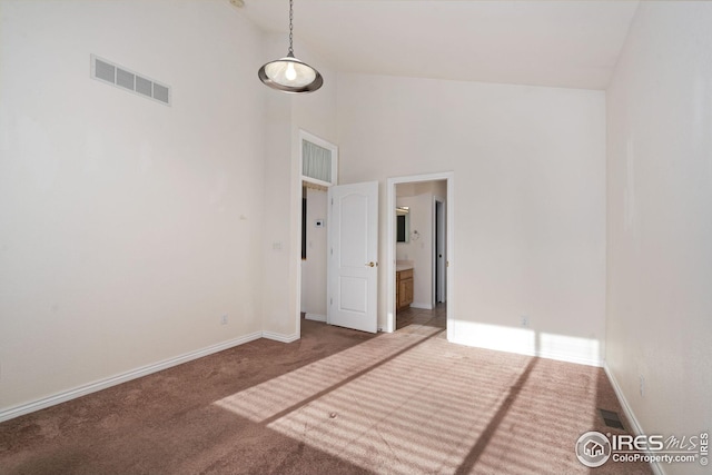 empty room with carpet and high vaulted ceiling