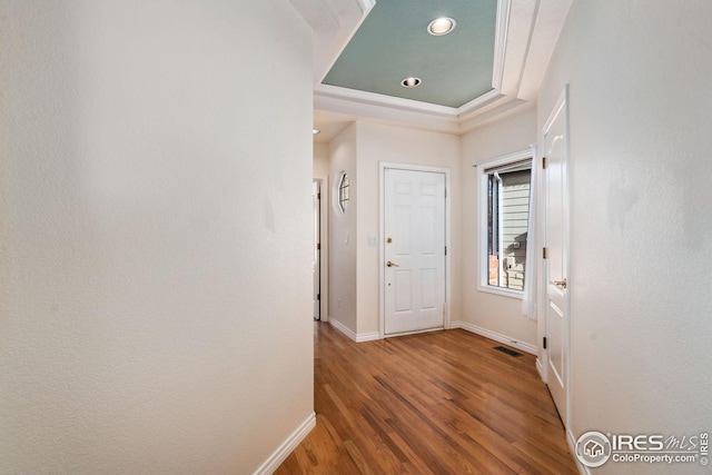 hallway featuring hardwood / wood-style floors and a tray ceiling