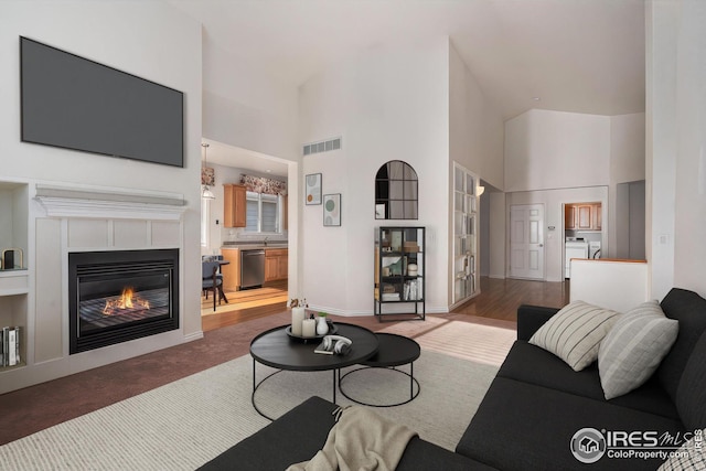 living room featuring sink, a towering ceiling, and washing machine and clothes dryer