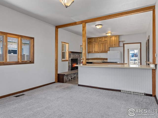 kitchen featuring a fireplace, white fridge, and light colored carpet