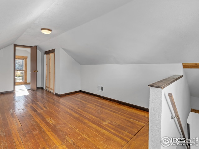 additional living space featuring dark wood-type flooring and lofted ceiling