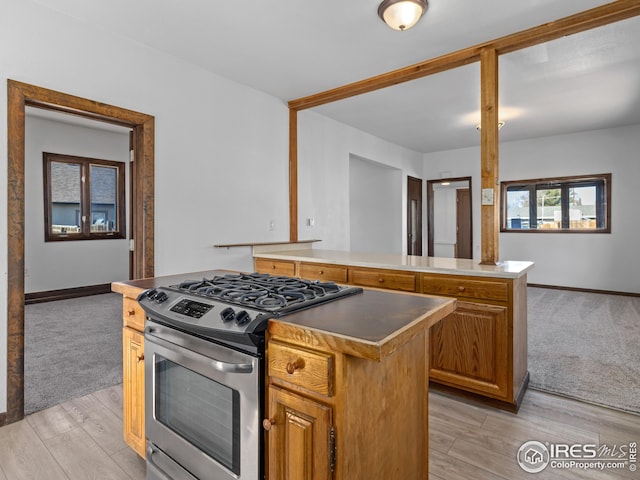 kitchen with a kitchen island, light wood-type flooring, and stainless steel gas range