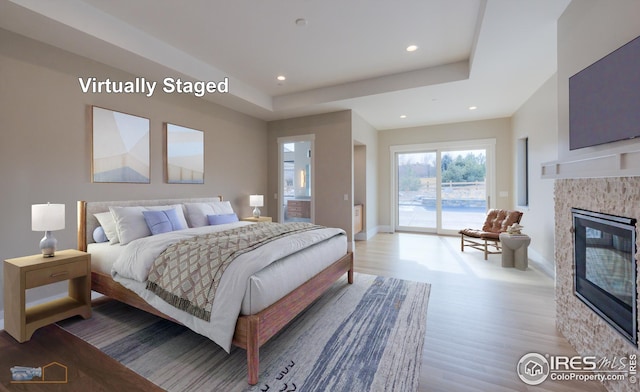 bedroom with access to outside, wood finished floors, recessed lighting, baseboards, and a tile fireplace