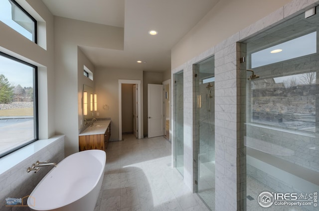 full bathroom with a tile shower, recessed lighting, a freestanding bath, and vanity