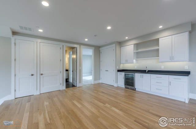 kitchen featuring open shelves, light wood-style flooring, recessed lighting, wine cooler, and dark countertops