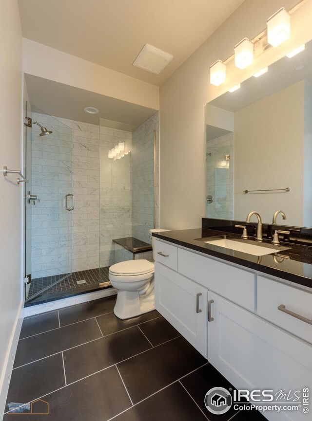 bathroom featuring vanity, toilet, a stall shower, and tile patterned flooring