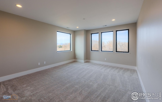 empty room featuring light colored carpet, recessed lighting, and baseboards
