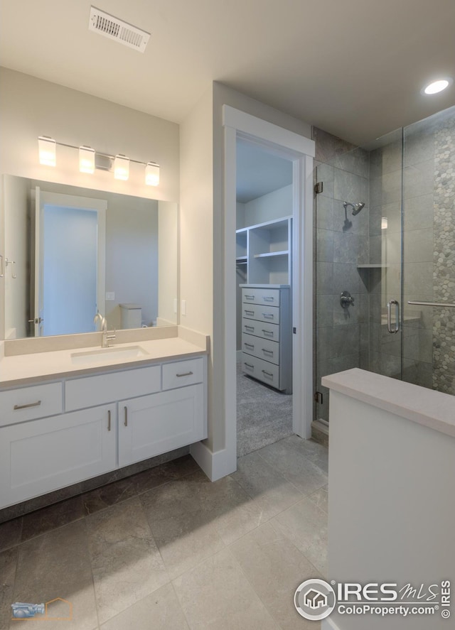 bathroom with visible vents, a shower stall, a walk in closet, recessed lighting, and vanity