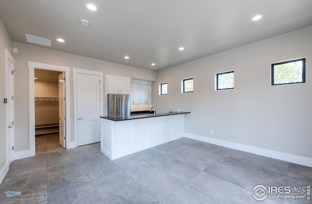 kitchen featuring visible vents, a peninsula, recessed lighting, high end refrigerator, and dark countertops