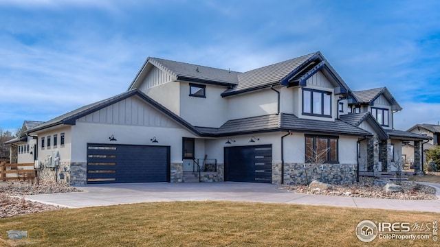 view of front of house featuring stone siding, a garage, concrete driveway, and a front yard