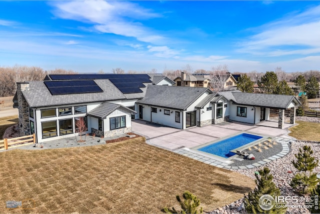 back of house featuring stucco siding, a lawn, stone siding, a patio, and fence