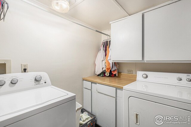 clothes washing area featuring washing machine and clothes dryer and cabinets