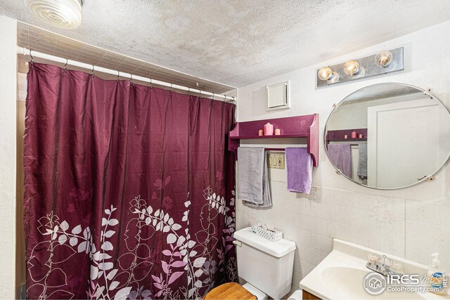 bathroom featuring a shower with curtain, vanity, toilet, and a textured ceiling