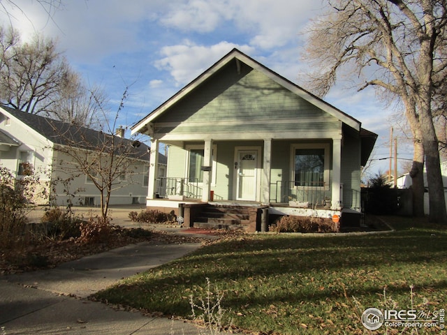 bungalow featuring covered porch and a front yard