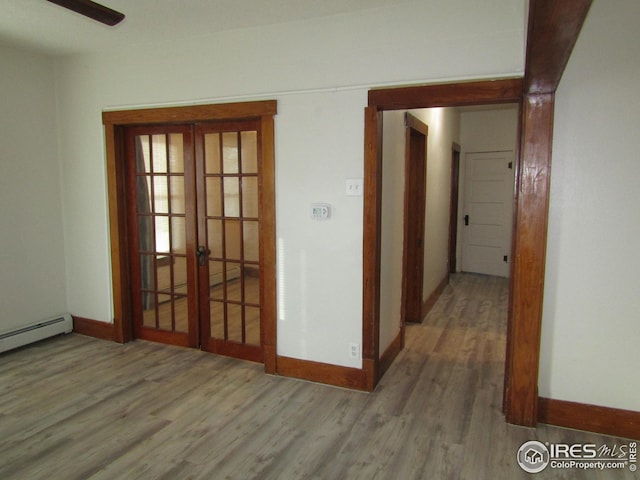 hall with baseboard heating, french doors, and hardwood / wood-style floors