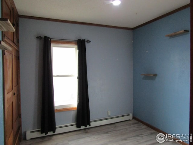 unfurnished room with light wood-type flooring, crown molding, and a baseboard heating unit