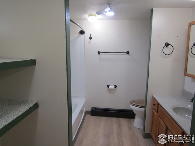 bathroom featuring ceiling fan, baseboard heating, wood-type flooring, toilet, and vanity