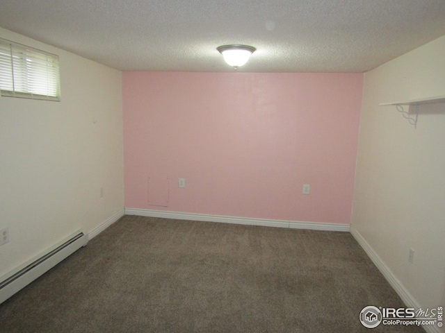 spare room with dark colored carpet, a textured ceiling, and a baseboard heating unit