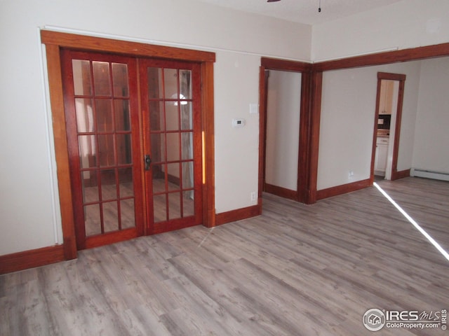 unfurnished room with ceiling fan, light hardwood / wood-style floors, a baseboard heating unit, and french doors