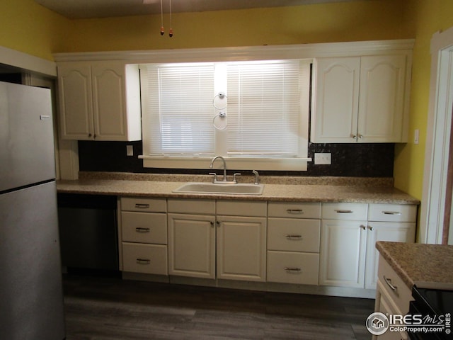 kitchen with stainless steel dishwasher, dark wood-type flooring, sink, white refrigerator, and white cabinets