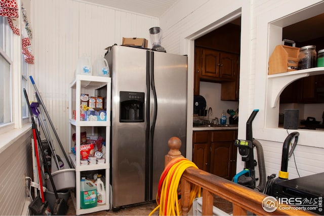 kitchen featuring sink, wooden walls, and stainless steel fridge with ice dispenser