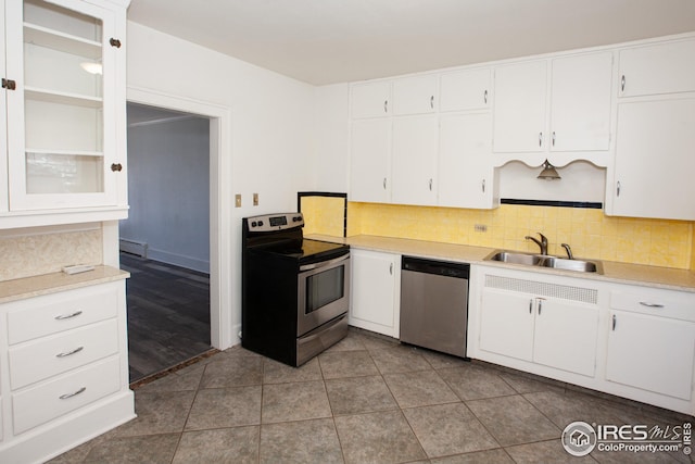 kitchen featuring sink, white cabinetry, baseboard heating, appliances with stainless steel finishes, and backsplash