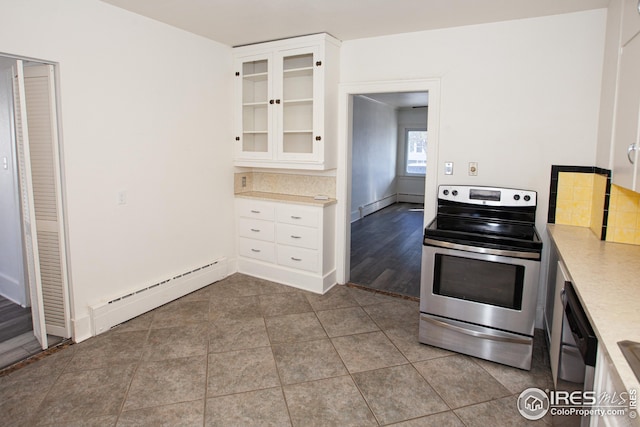 kitchen featuring stainless steel electric range oven, light tile patterned floors, a baseboard radiator, white cabinets, and backsplash