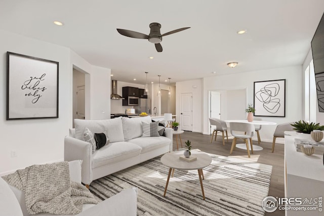 living room with dark hardwood / wood-style floors, ceiling fan, and sink