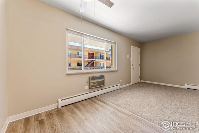 empty room with baseboard heating, a wall unit AC, and hardwood / wood-style flooring