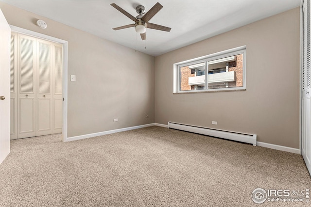 carpeted empty room with ceiling fan and a baseboard heating unit